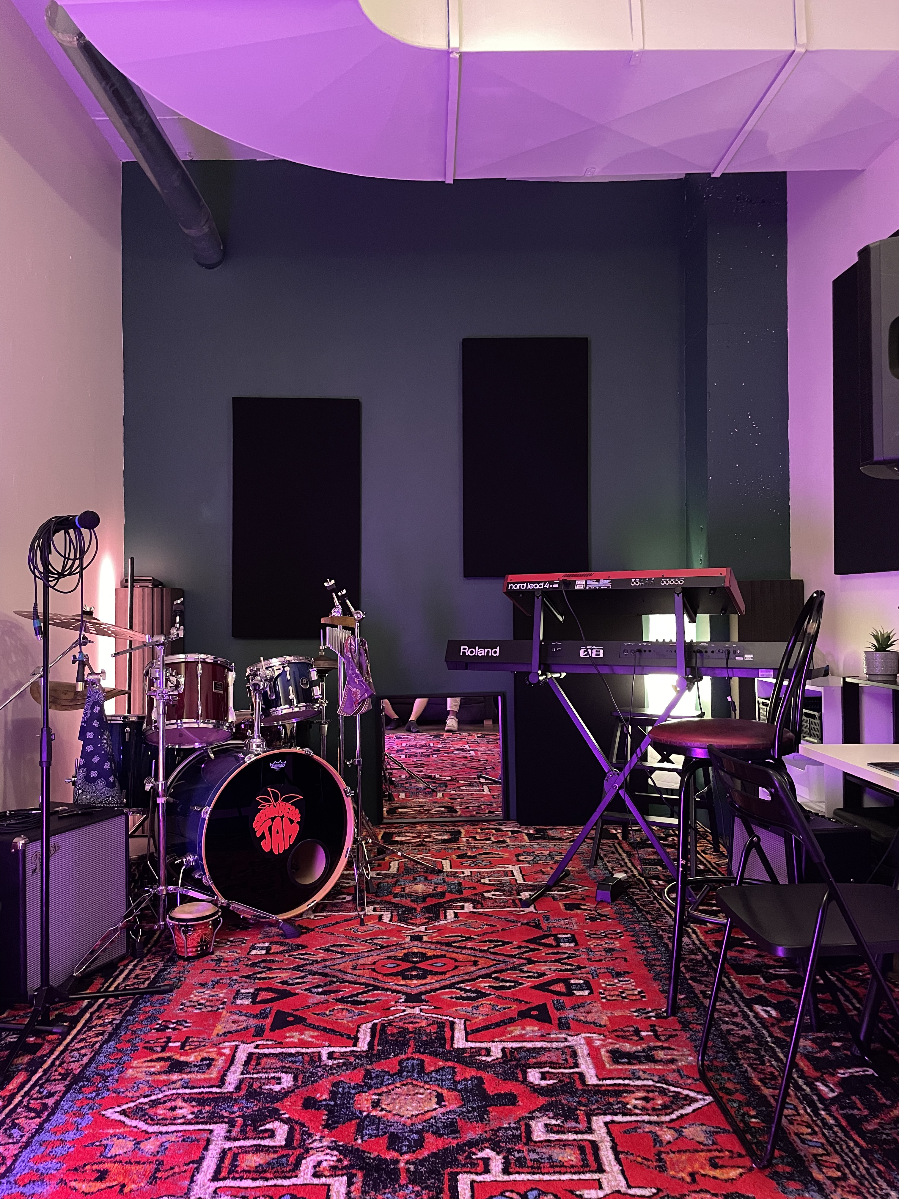 Wide angle of rehearsal room with drum kit and amps